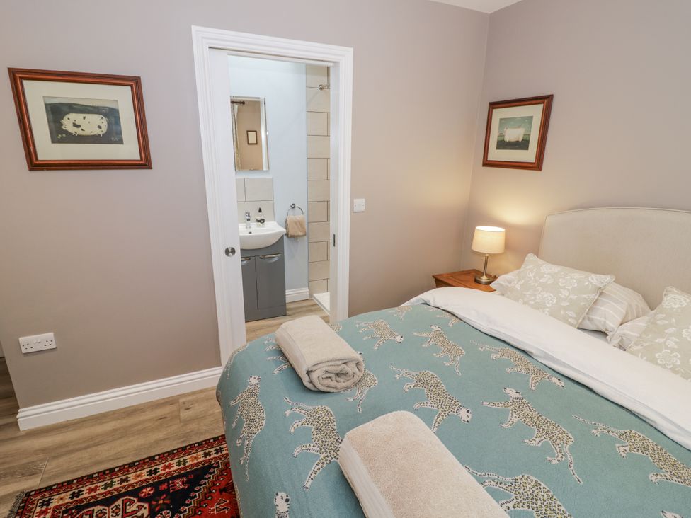 A bedroom with a bed and a bathroom door at Lily Stables in Black Bourton near Bampton, Oxfordshire