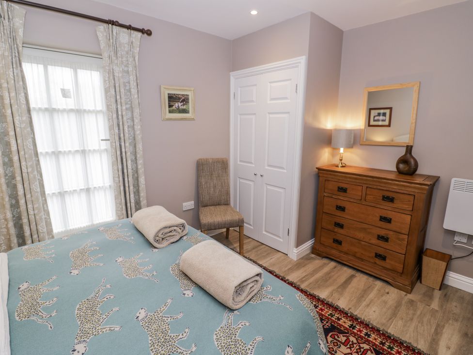 A bedroom with a bed and a chair at Lily Stables in Black Bourton near Bampton, Oxfordshire