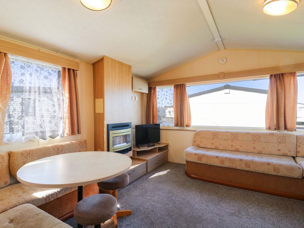 A living room with a sofa, table, and television at Luisa Family Caravan St. Osyth