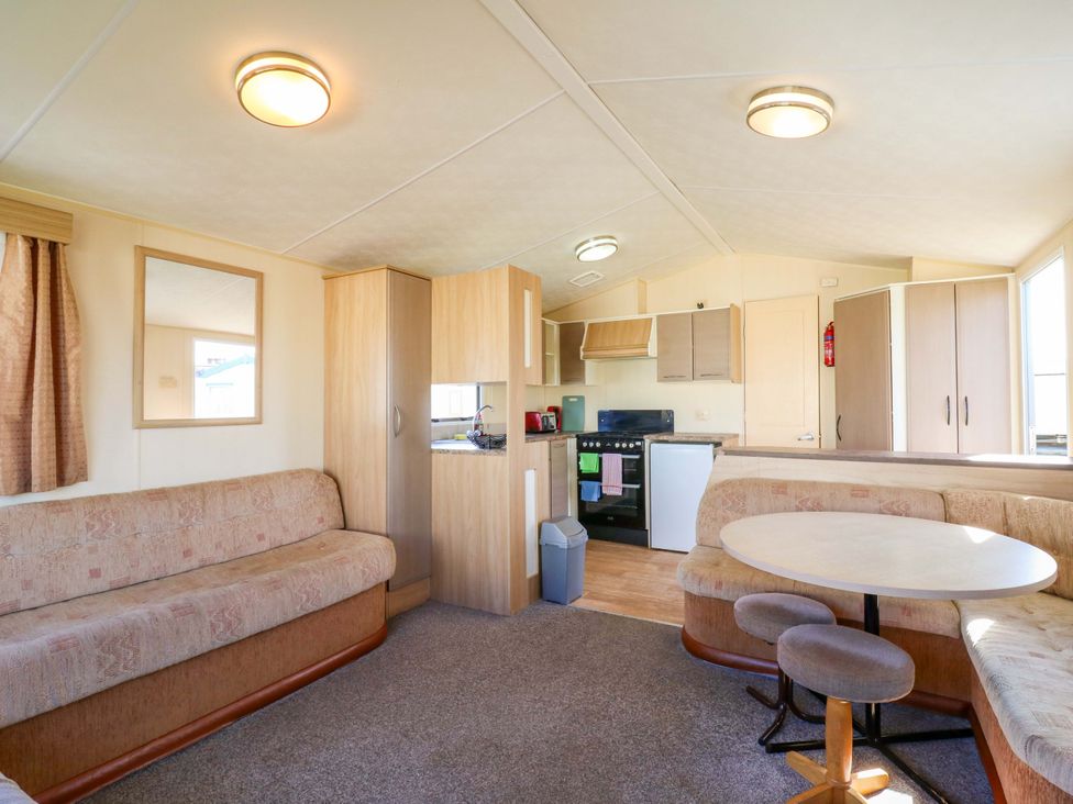 A living room with a sofa, kitchen and table at Luisa Family Caravan St. Osyth