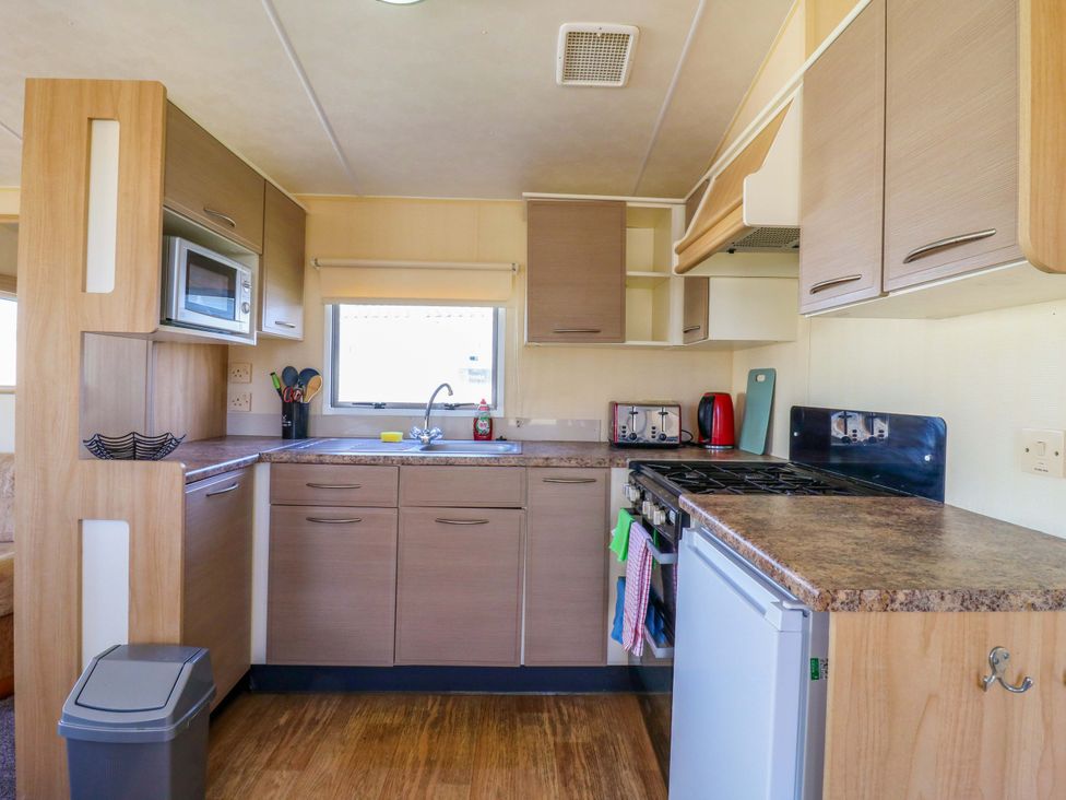 A kitchen with cabinets and appliances at Luisa Family Caravan in St. Osyth