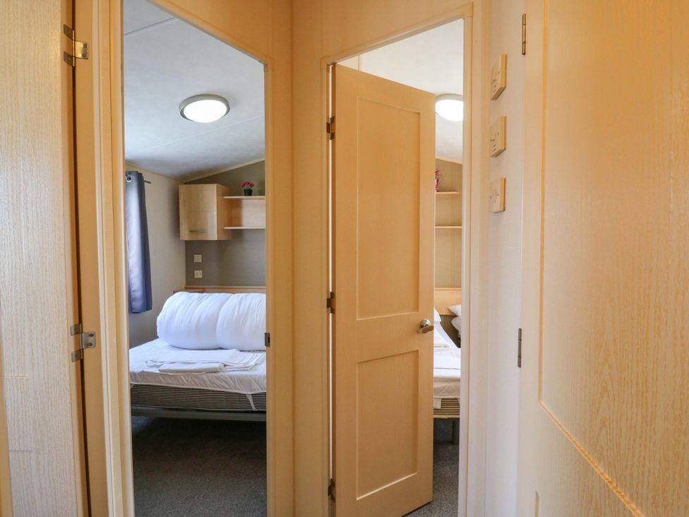 A bedroom with a bed and shelves at Luisa Family Caravan in St. Osyth