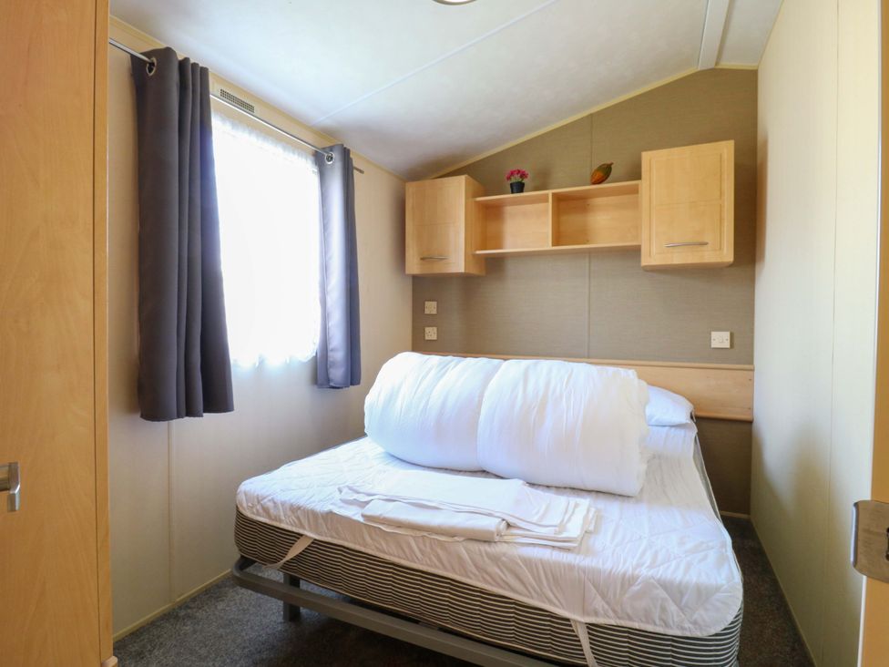 A bedroom with a bed and shelving at Luisa Family Caravan St. Osyth