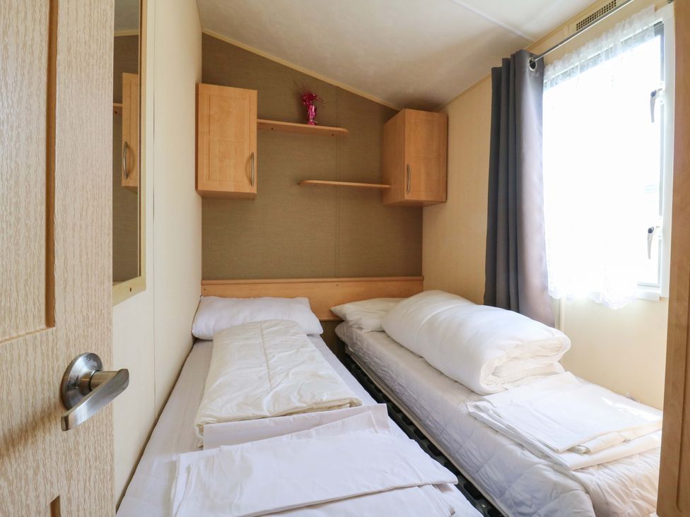 A bedroom with two beds and a shelf at Luisa Family Caravan St. Osyth