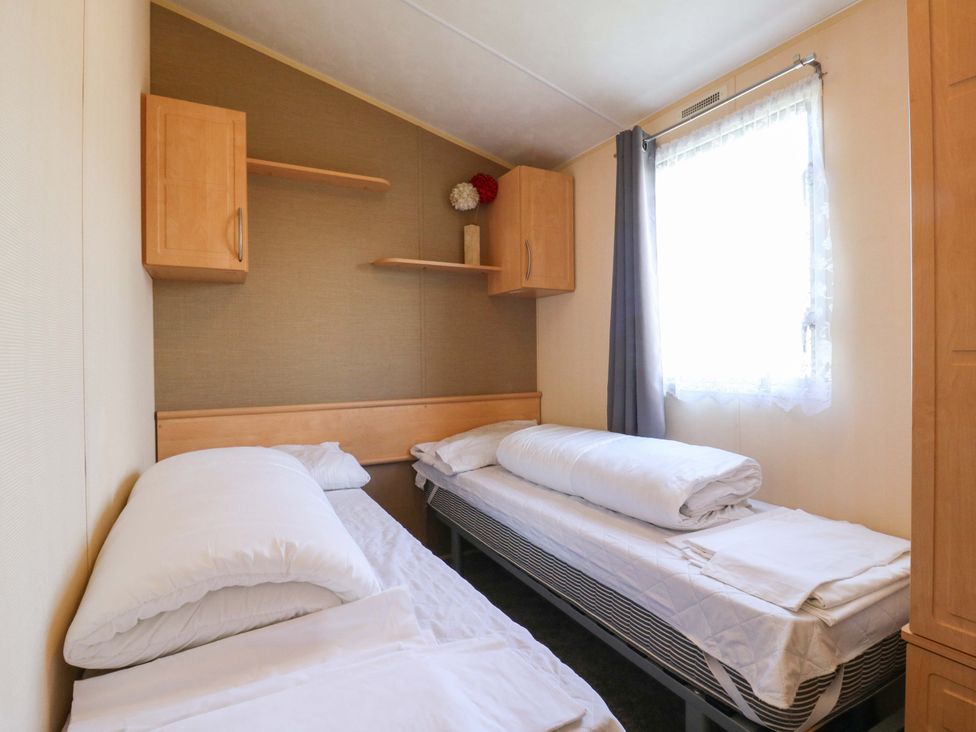 A bedroom with two beds and storage at Luisa Family Caravan St. Osyth