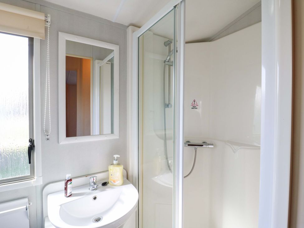 A bathroom with a shower, washbasin, and mirror at Luisa Family Caravan St. Osyth