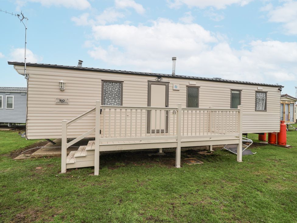 A caravan with a wooden deck and gas tanks at Singh Leite & Luisa Family Caravan in St. Osyth