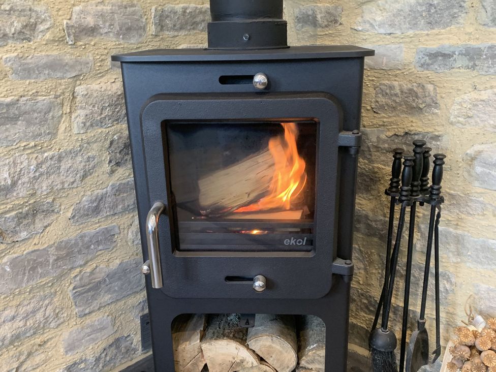A wood stove with a fire burning at Rose Stables Black Bourton near Bampton