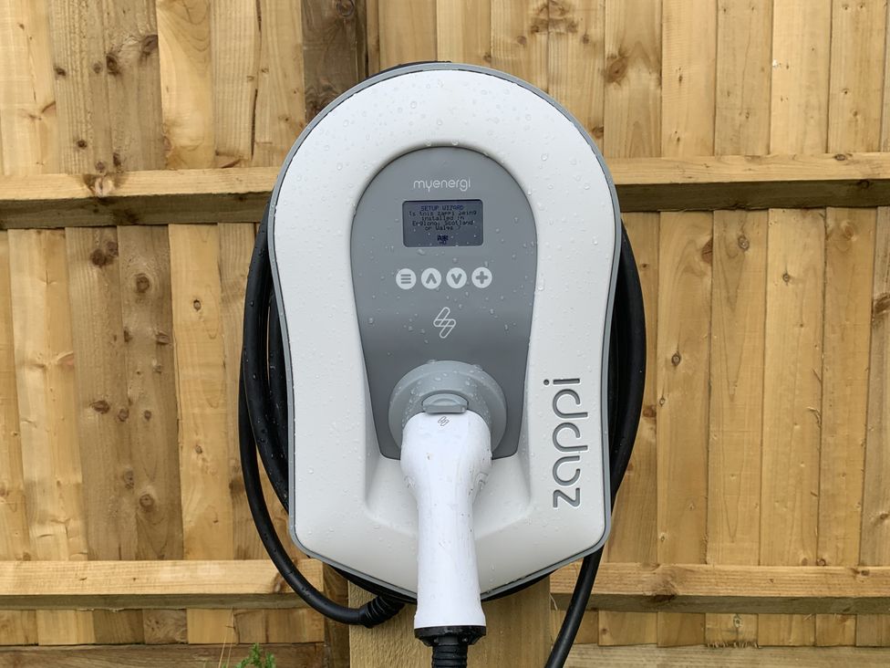 An electric car charger mounted on a wooden fence at Rose Stables Black Bourton near Bampton
