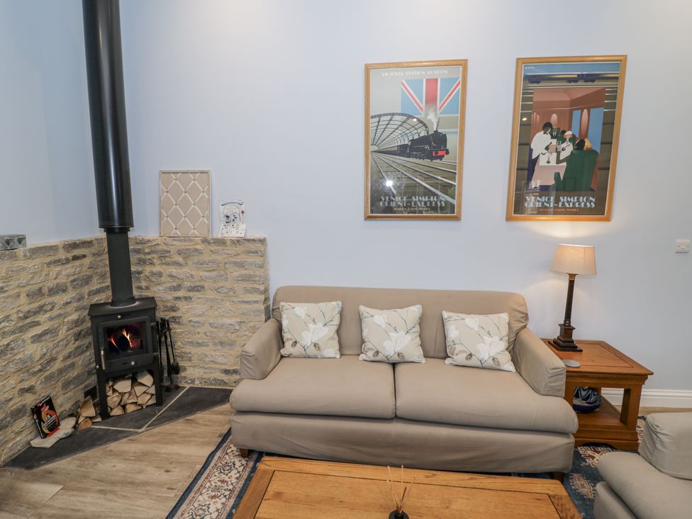 A living room with a sofa and wood stove at Rose Stables near Black Bourton