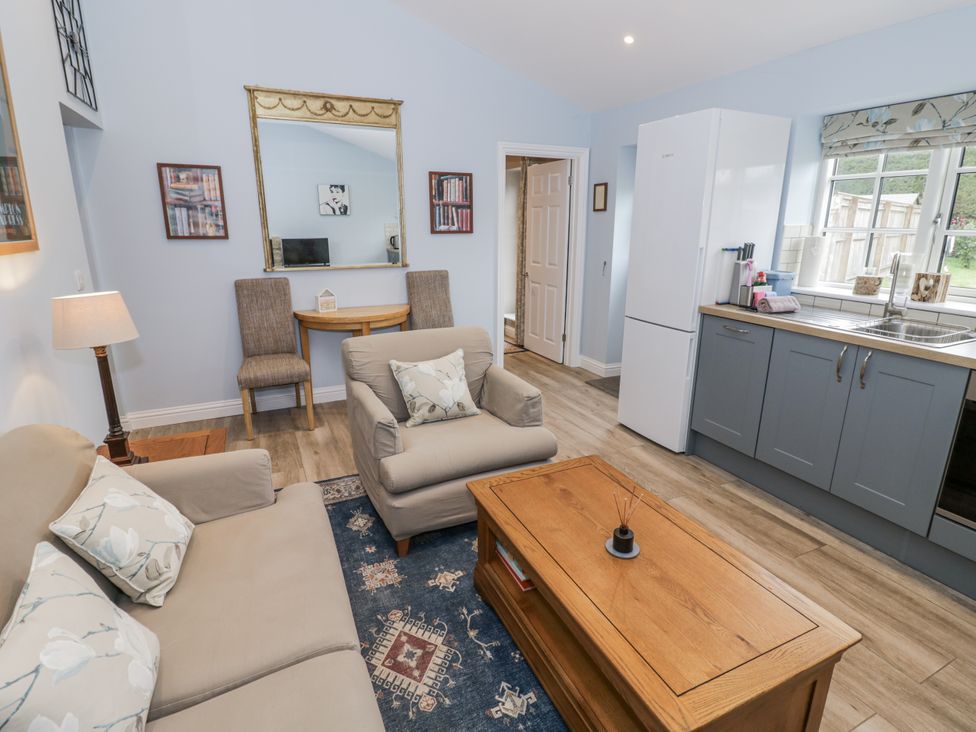 A living room with a sofa, armchair, and dining table at Rose Stables Black Bourton near Bampton