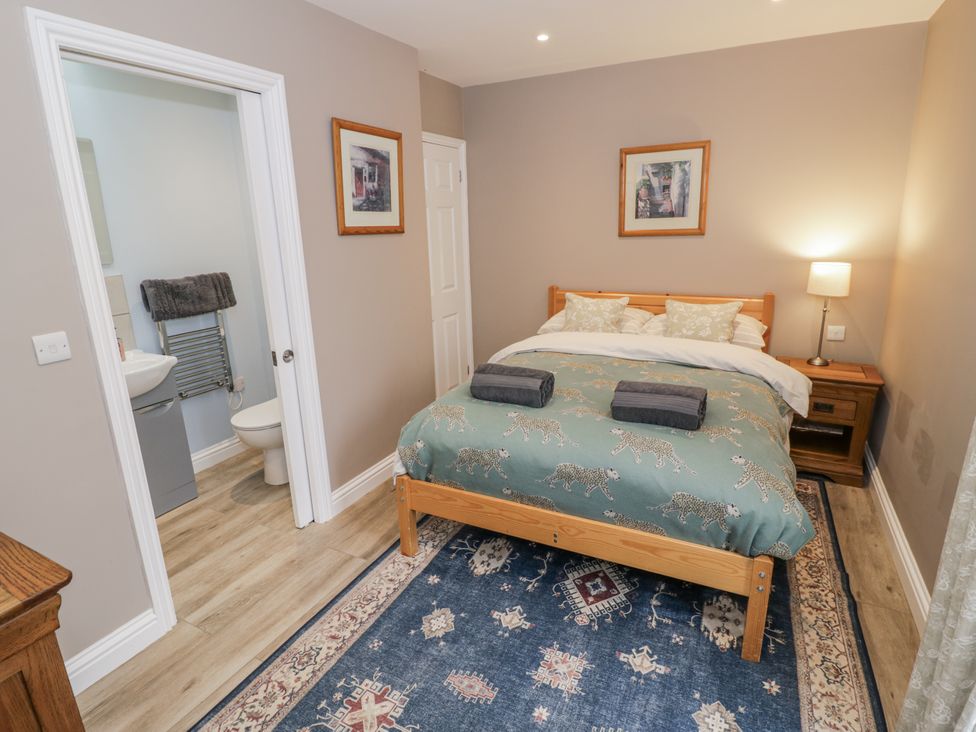 A bedroom with a bed and bathroom access at Rose Stables near Bampton