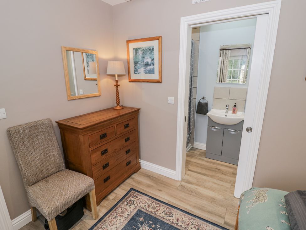 A bedroom with a chest of drawers and an adjoining bathroom at Rose Stables Black Bourton near Bampton