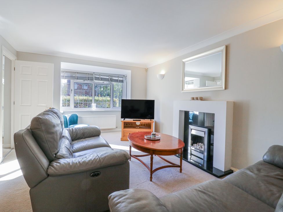 A living room with a sofa, coffee table, and television at 32 Abbey Gardens
