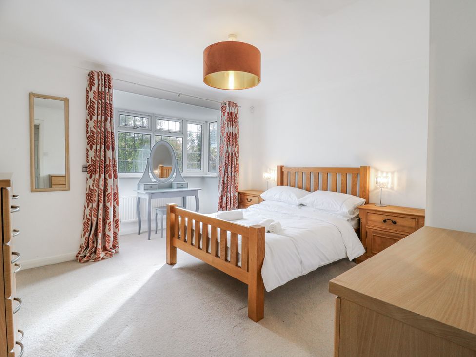 A bedroom with a wooden bed and mirror at 32 Abbey Gardens