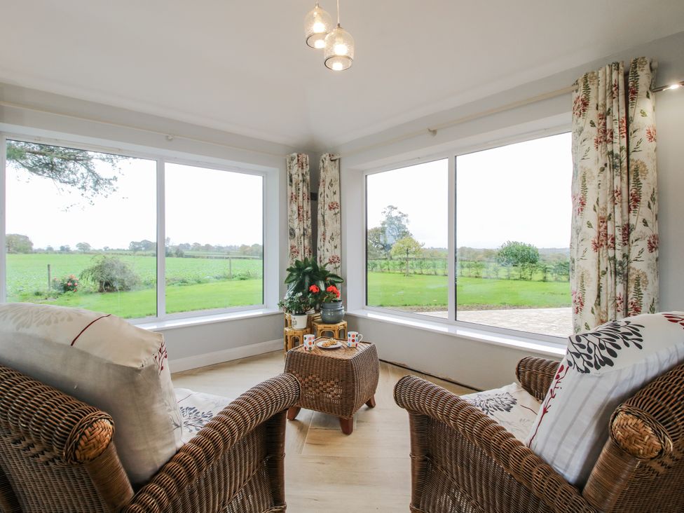 A conservatory with armchairs and a coffee table at Garden Cottage in Ellesmere