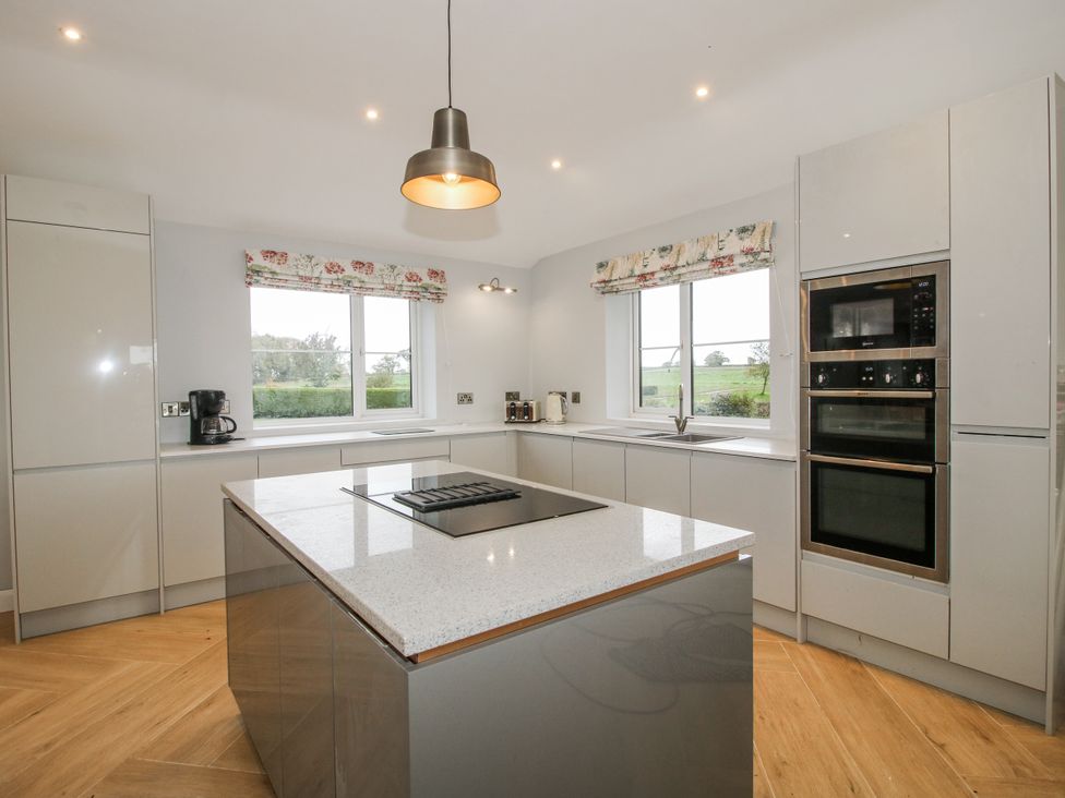 A kitchen with a kitchen island and windows at Garden Cottage in Ellesmere
