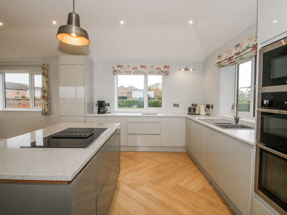 A kitchen with a central island and appliances at Garden Cottage in Ellesmere