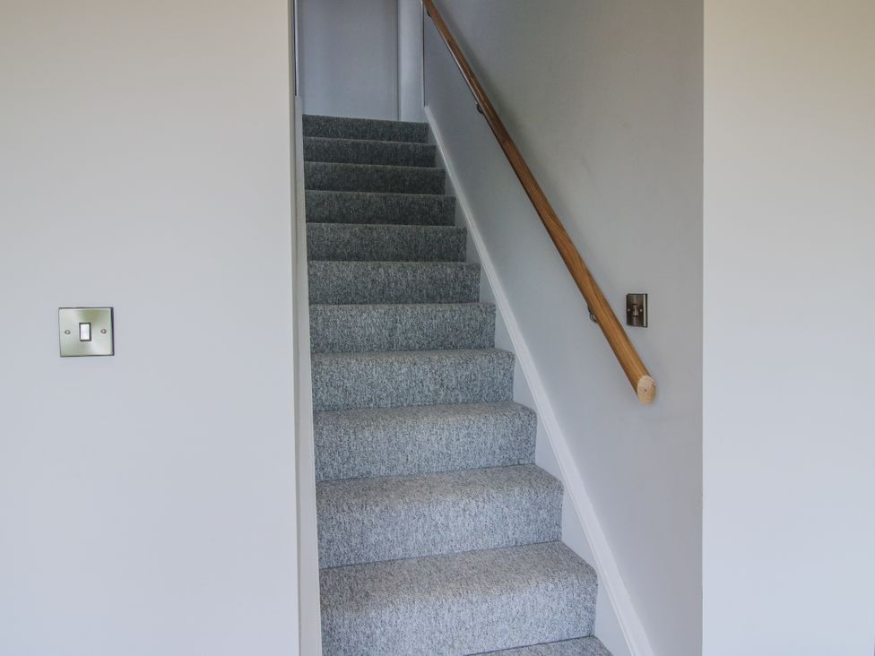 A staircase leading up with a handrail at Garden Cottage in Ellesmere