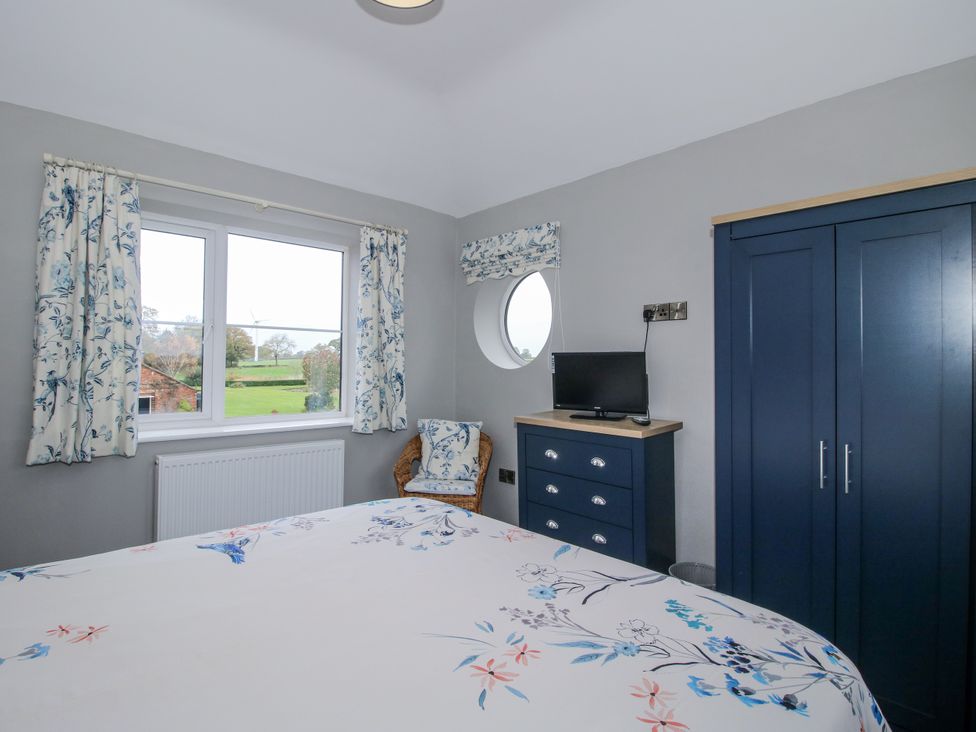 A bedroom with a bed and window at Garden Cottage in Ellesmere