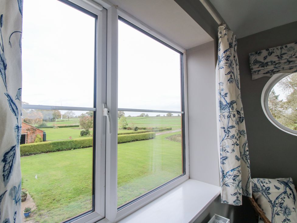 A garden room with a view of a lawn and hedges at Garden Cottage in Ellesmere