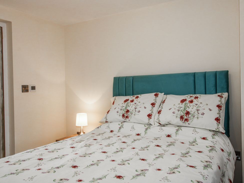A bedroom with a bed and bedside lamp at Garden Cottage in Ellesmere