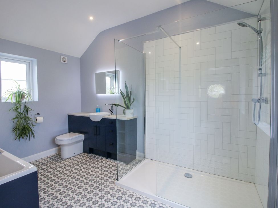 A bathroom with a shower, toilet and vanity at Garden Cottage in Ellesmere