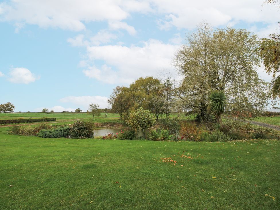 A garden with a pond and trees at Garden Cottage in Ellesmere