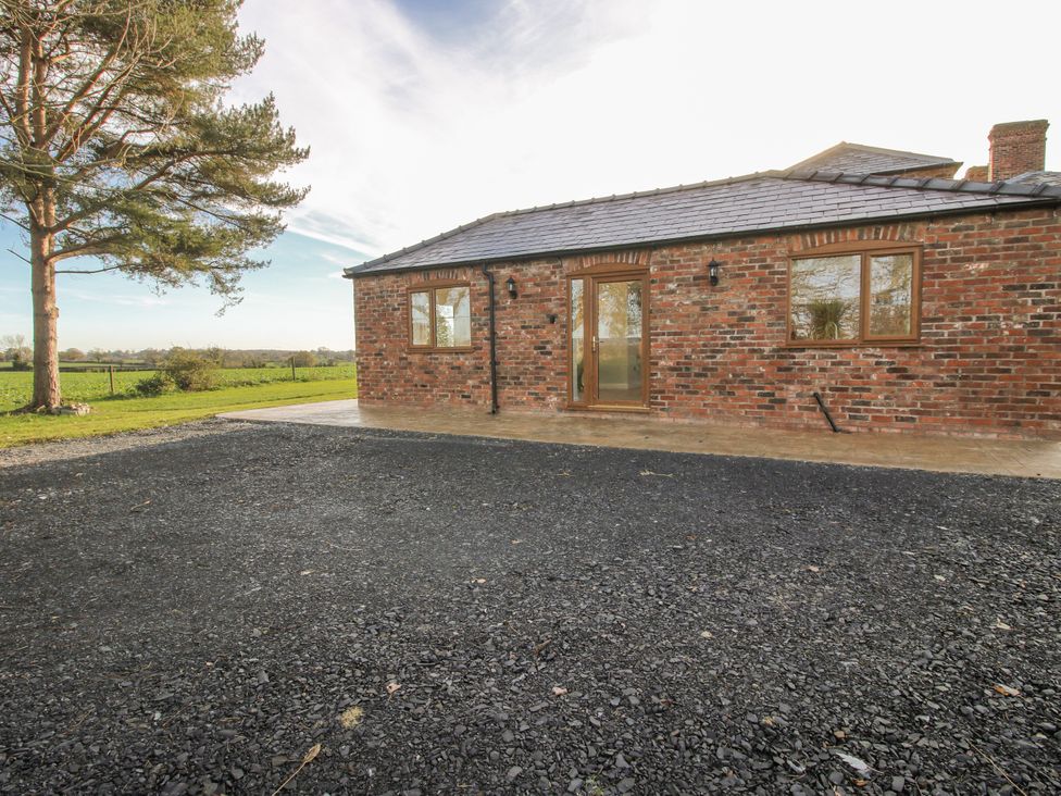 An exterior view of a brick cottage with a gravel area at Garden Cottage in Cockshutt