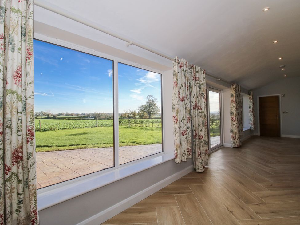 A living room with large windows and curtains at Garden Cottage in Cockshutt