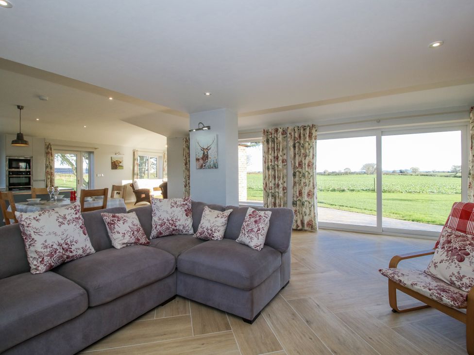 A living room with a sofa and dining area at Garden Cottage in Cockshutt