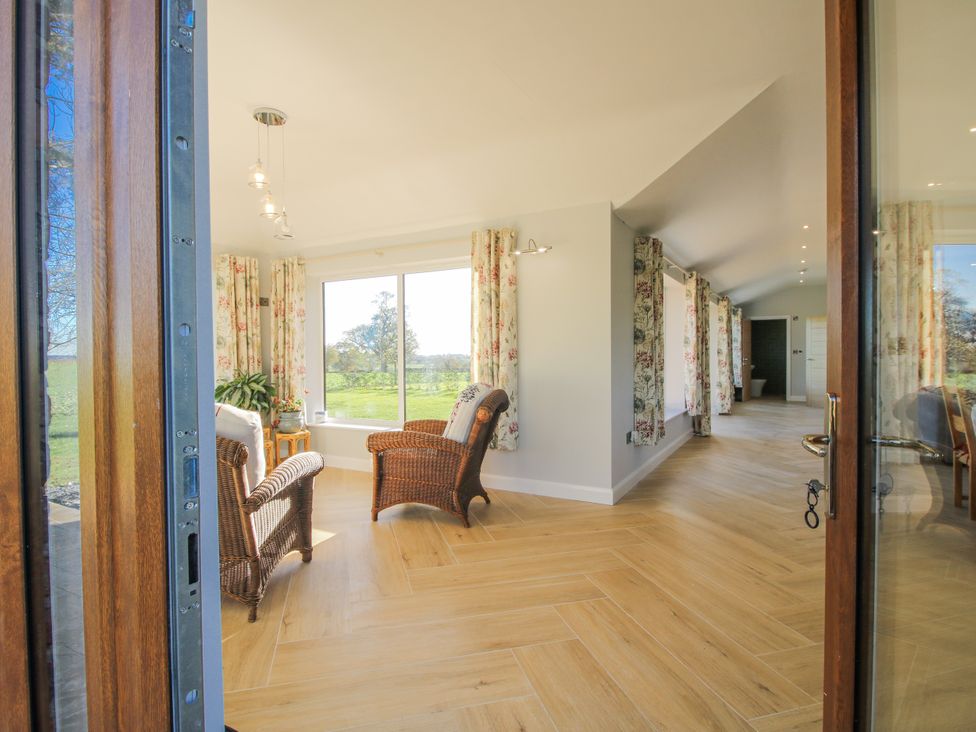 A conservatory with seating and large windows at Garden Cottage in Cockshutt