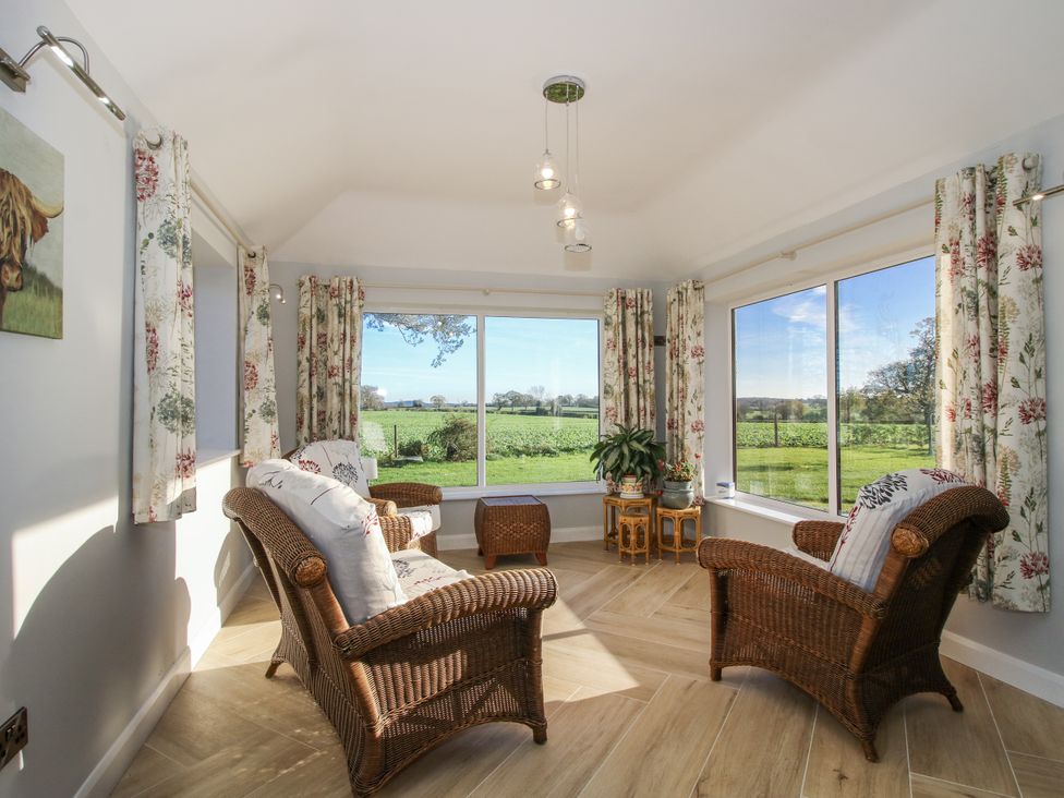 A conservatory with chairs and a table at Garden Cottage in Cockshutt