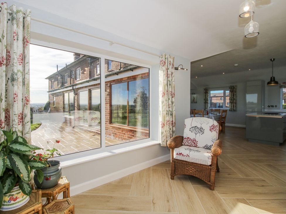 A living room with a chair and view of the garden at Garden Cottage in Cockshutt
