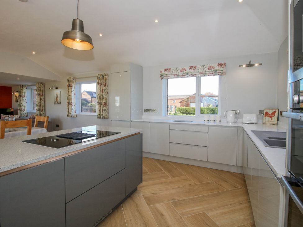 A kitchen with cabinets and windows at Garden Cottage in Cockshutt