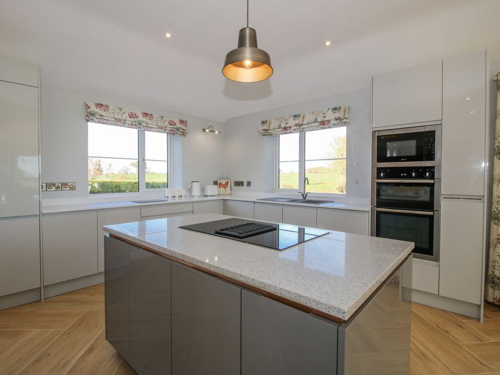 A kitchen with a cooking range and windows at Garden Cottage in Cockshutt
