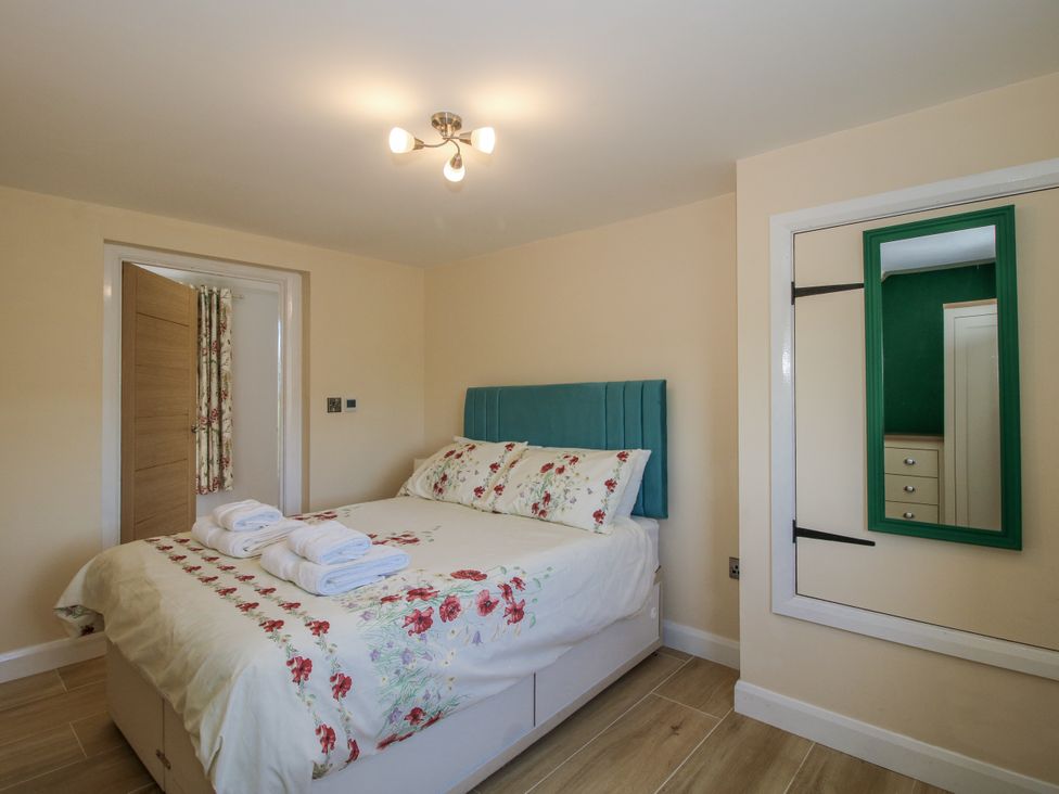 A bedroom with a bed and a mirror at Garden Cottage in Cockshutt