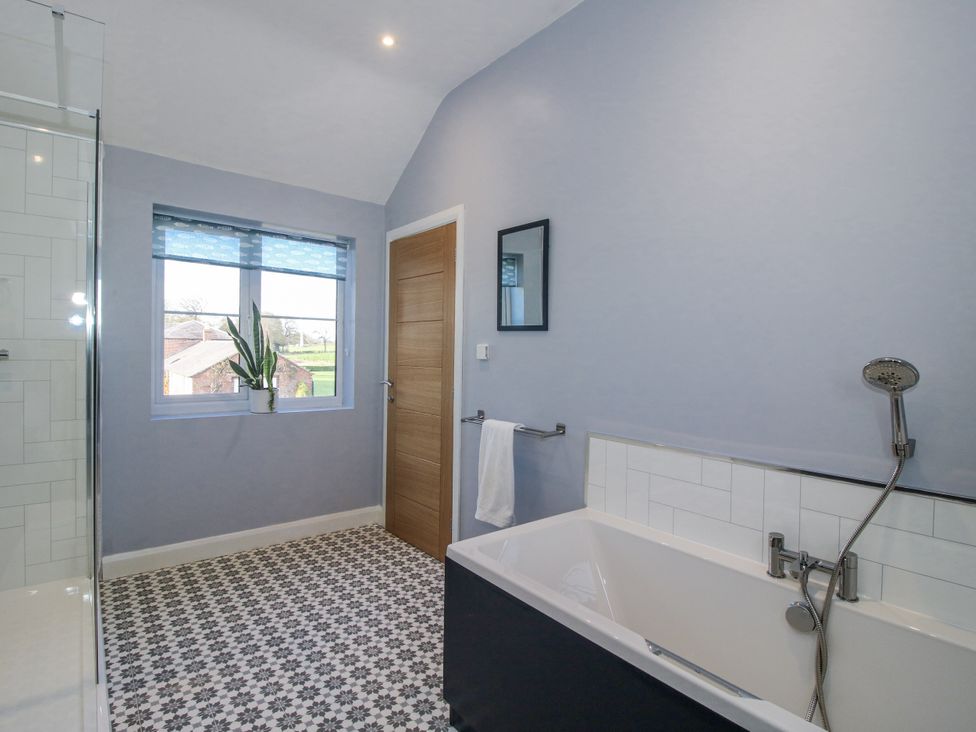 A bathroom with a bathtub and shower at Garden Cottage in Cockshutt