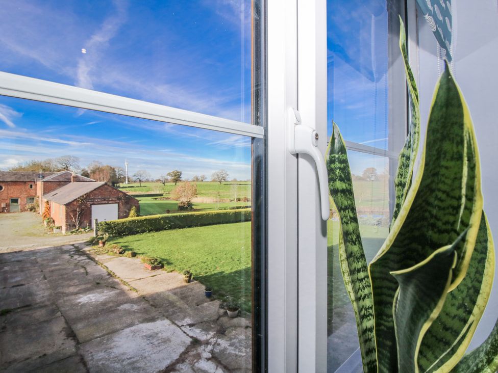 A view from a window showing a farm and grass at Garden Cottage in Cockshutt