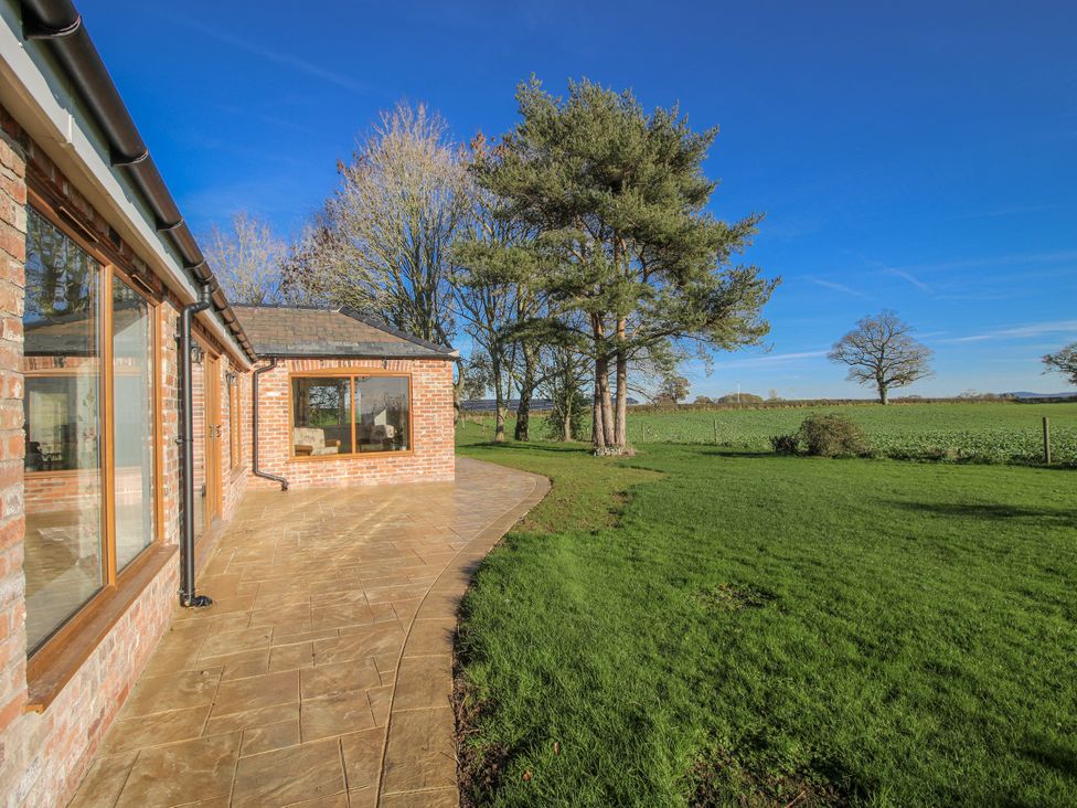 An outdoor view with a patio and lawn at Garden Cottage in Cockshutt