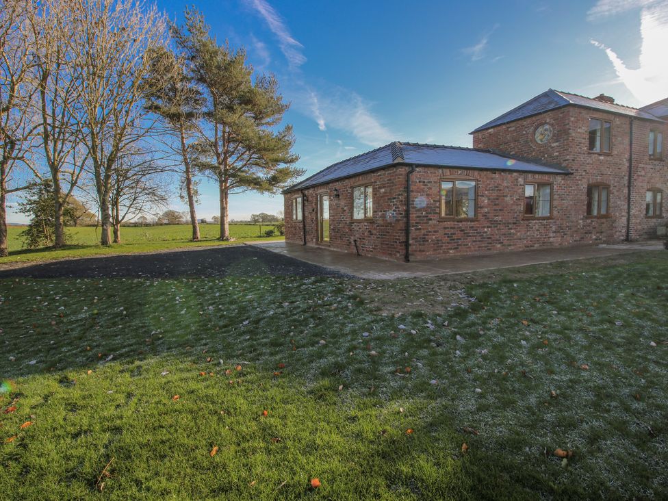 An exterior view of a brick building with trees and grass at Garden Cottage in Cockshutt