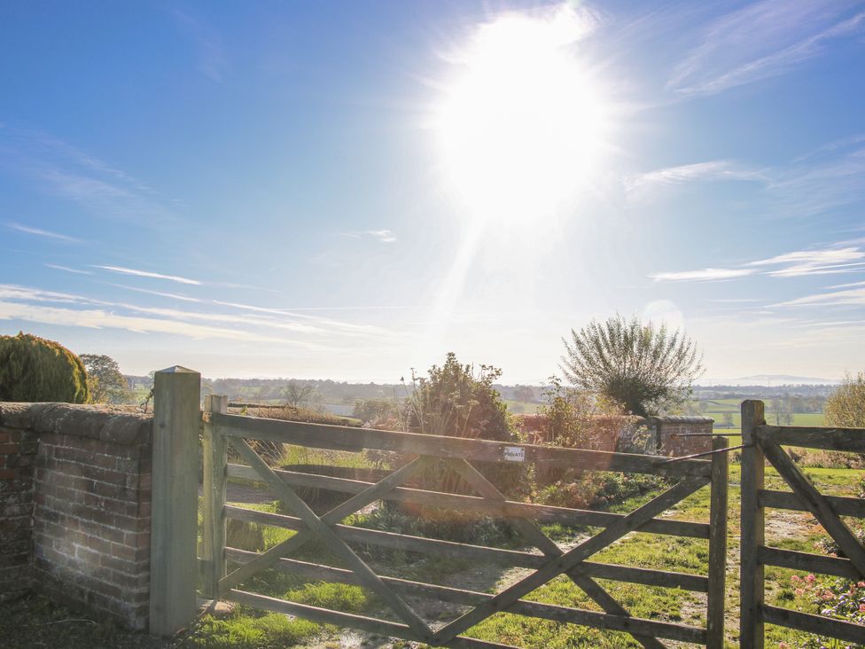 A gate leading to a field with trees and a wall at Garden Cottage in Cockshutt
