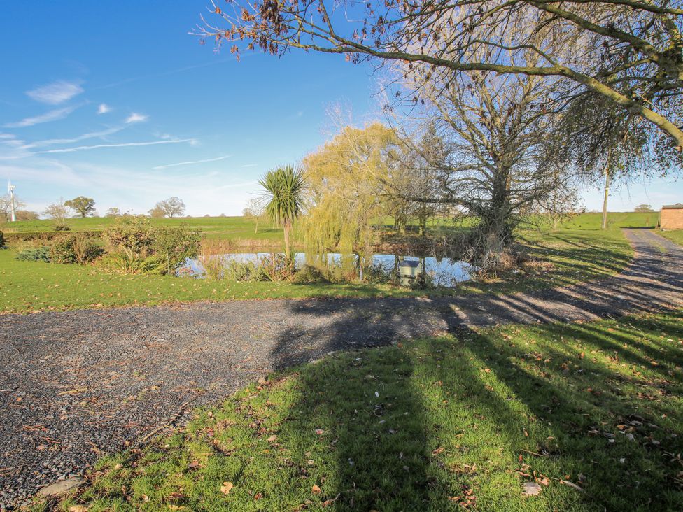 A pond surrounded by grass and trees at Garden Cottage in Cockshutt