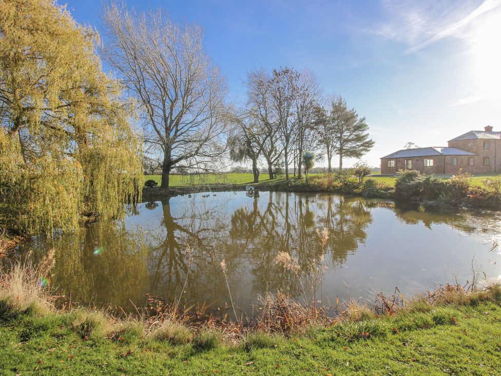A garden with a pond and trees at Garden Cottage in Cockshutt