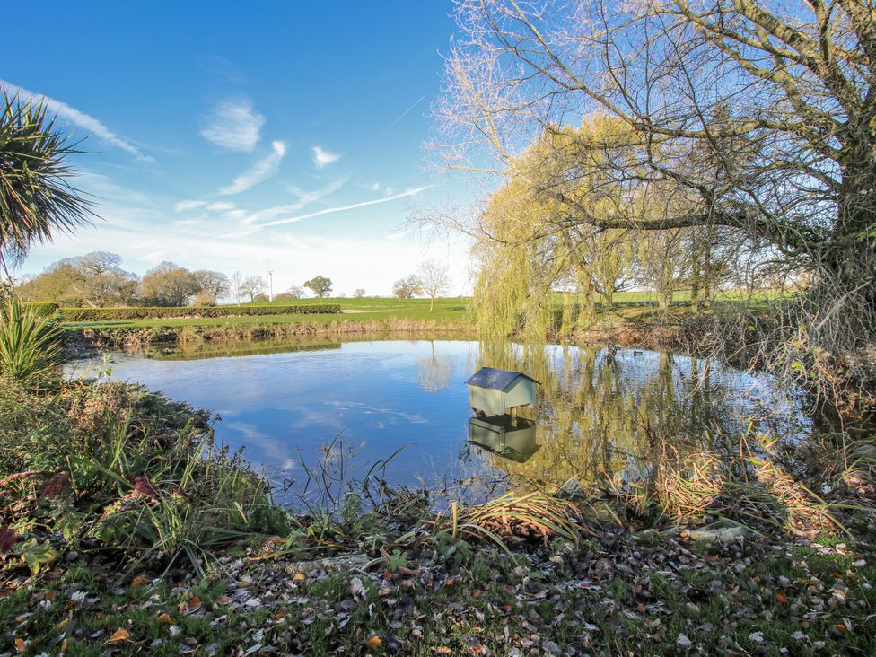 A pond with a duck house and trees beside at Garden Cottage in Cockshutt