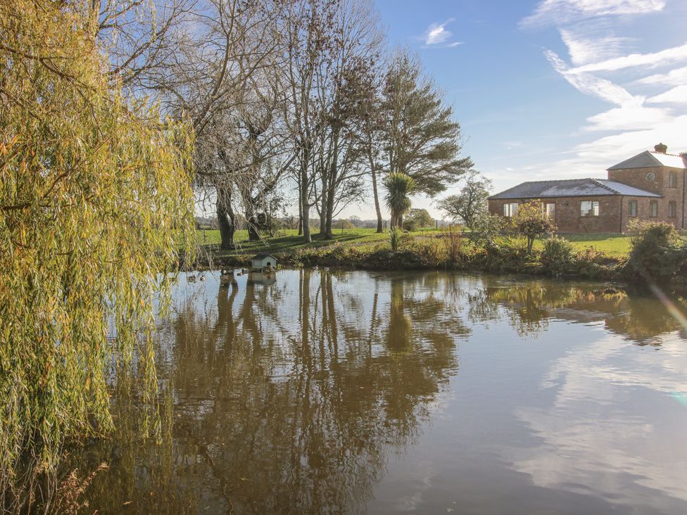 A pond with reflections and trees at Garden Cottage in Cockshutt