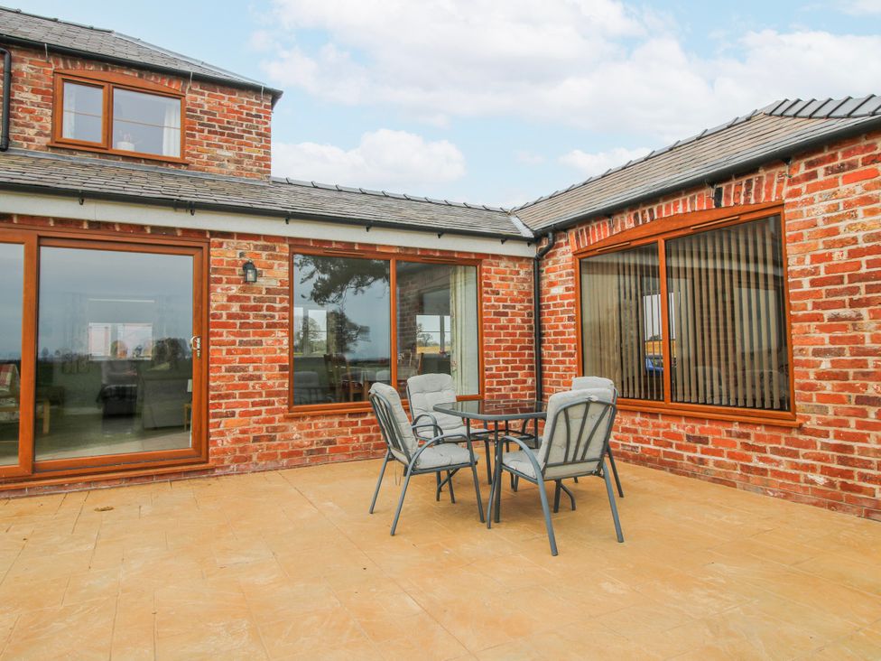 An outdoor terrace with a table and chairs at Garden Cottage in Cockshutt