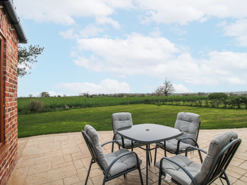 A patio area with a table and chairs at Garden Cottage in Cockshutt