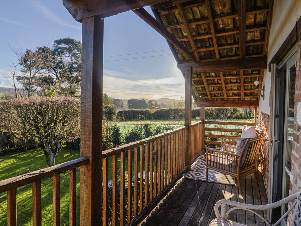 A balcony with wooden railing and chairs overlooking a garden at The Little Barn in Fluxton Nr. Ottery St Mary
