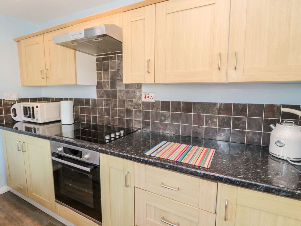 A kitchen with a microwave, kettle, oven, and stove at 23 Northumbria Terrace Amble